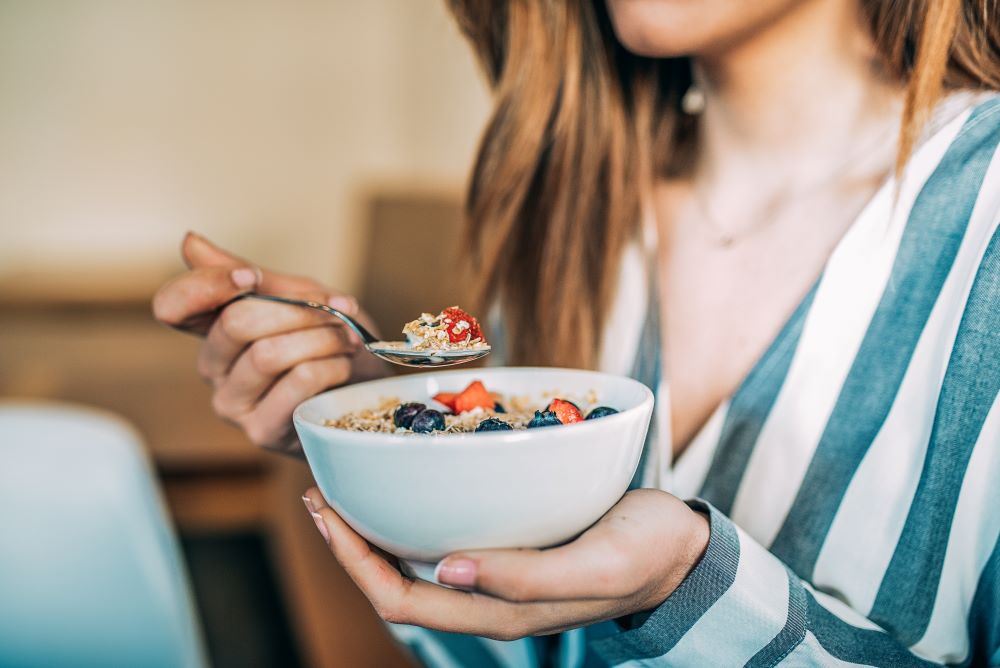 Femme mangeant un bol de fruits pour son petit déjeuner