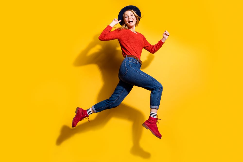 Femme heureuse qui saute en l'air sur un fond jaune
