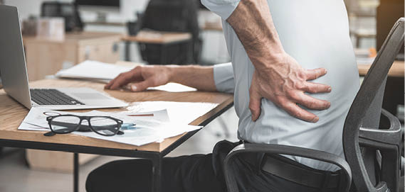 Homme qui a un mal au dos est assis à son bureau