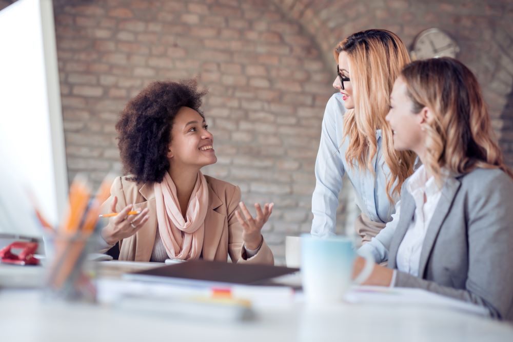 Trois femmes qui discutent autour d'une table au travail